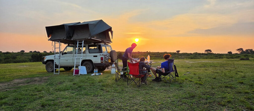 Rooftop tent and camping gear set up beside a rental 4x4 in Rwanda