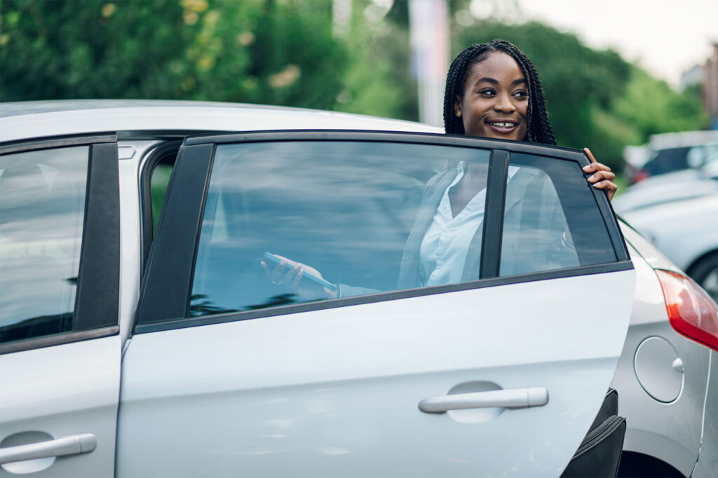 Smiling traveller getting into a rental car in Kigali